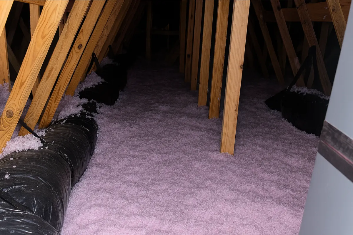 Fresh blown-in attic insulation surrounding HVAC ductwork in a Baltimore MD home, shown as part of an attic insulation upgrade by a local contractor.