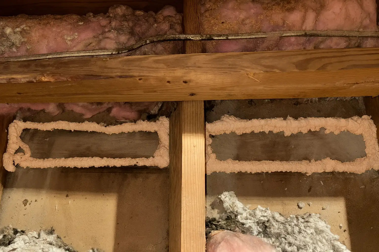 Close-up of attic joists showing spray foam air sealing and removed insulation during an inspection and prep process by an insulation contractor in Baltimore, MD.